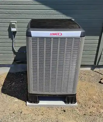 New Lennox condenser on a pad against grey siding