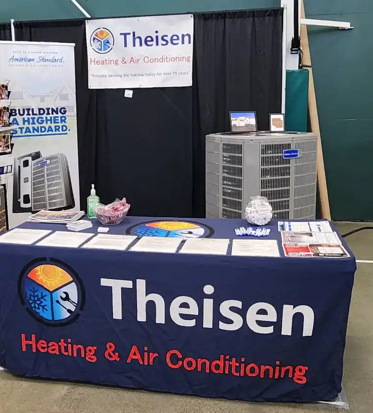 The Theisen home-show booth with a navy table cover, a banner and an American Standard condenser