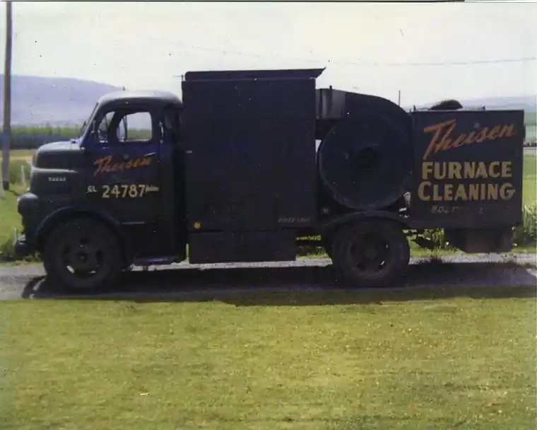 Theisen's vintage Furnace Cleaning truck parked in a field, GL 24787 lettered on the door