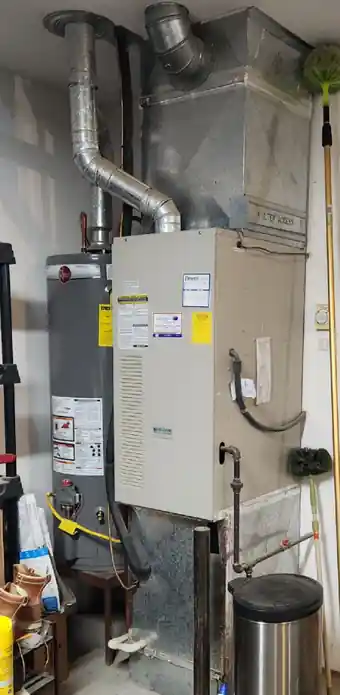 Old furnace and water heater in a utility room before replacement