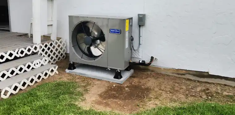 New American Standard heat pump on a pad beside lattice steps and lawn