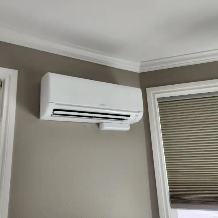 A white Mitsubishi ductless wall head mounted high in a grey living room