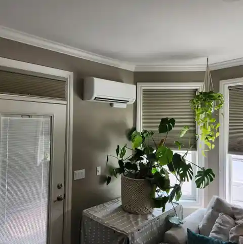 The same grey room seen wider, with houseplants and the ductless wall head above a window.