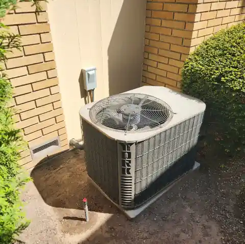 Old condenser beside a yellow brick wall before replacement