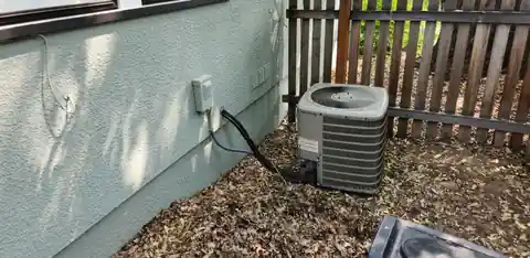 Old condenser beside a sage green wall and cedar fence