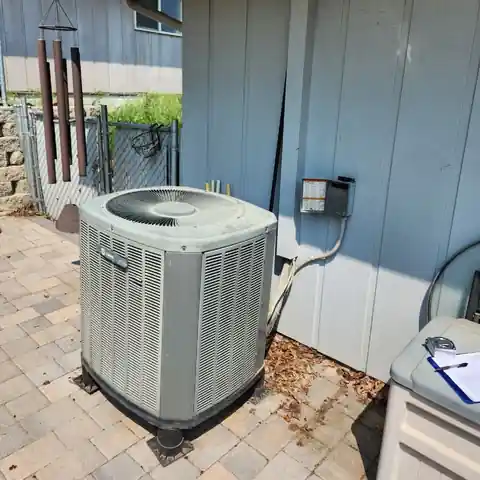 New American Standard condenser on pavers beside blue siding